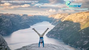 Man performing a handstand on a mountain peak against a breathtaking backdrop, symbolizing the triumph over challenging feats such as validating a foreign PhD in Italy